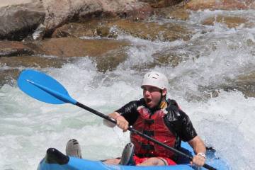 man with white helmet paddles through white water on the lower Animas River