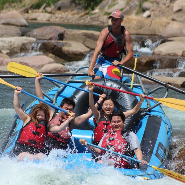 A group of rafters hold their paddles above their heads while white water rafting the lower Animas River