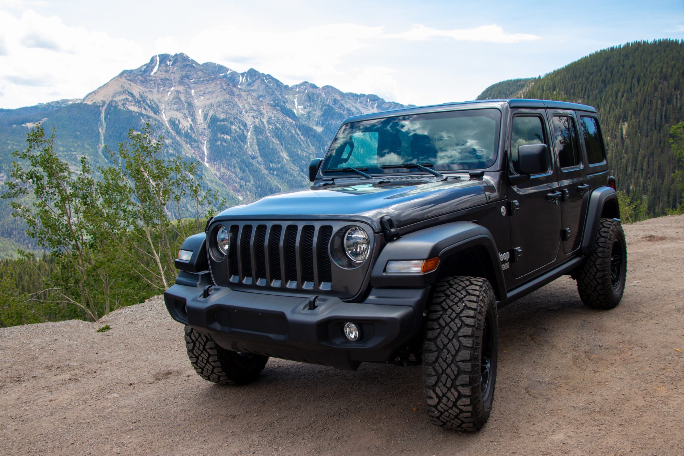 Durango Jeep Rentals A black Jeep is parked on a forest road in the Colorado wilderness with a large mountain in the background