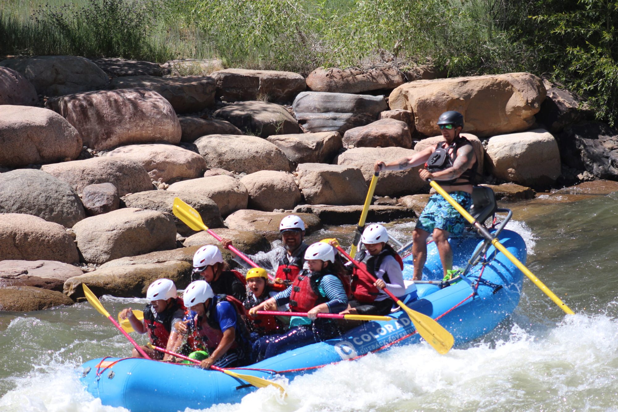 a group of people on a blue raft float down a rapid on a river