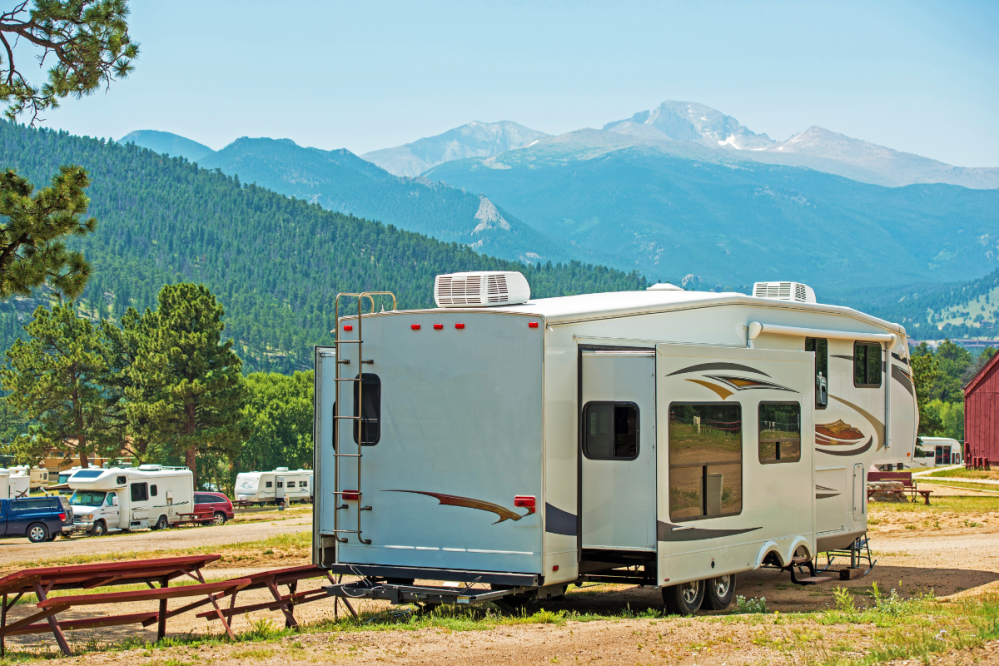 a travel trailer is parked at a campground with mountains in the background
