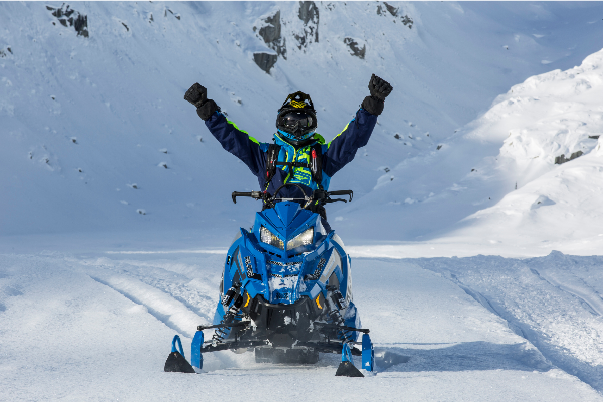 person snowmobiling with mountain in the background